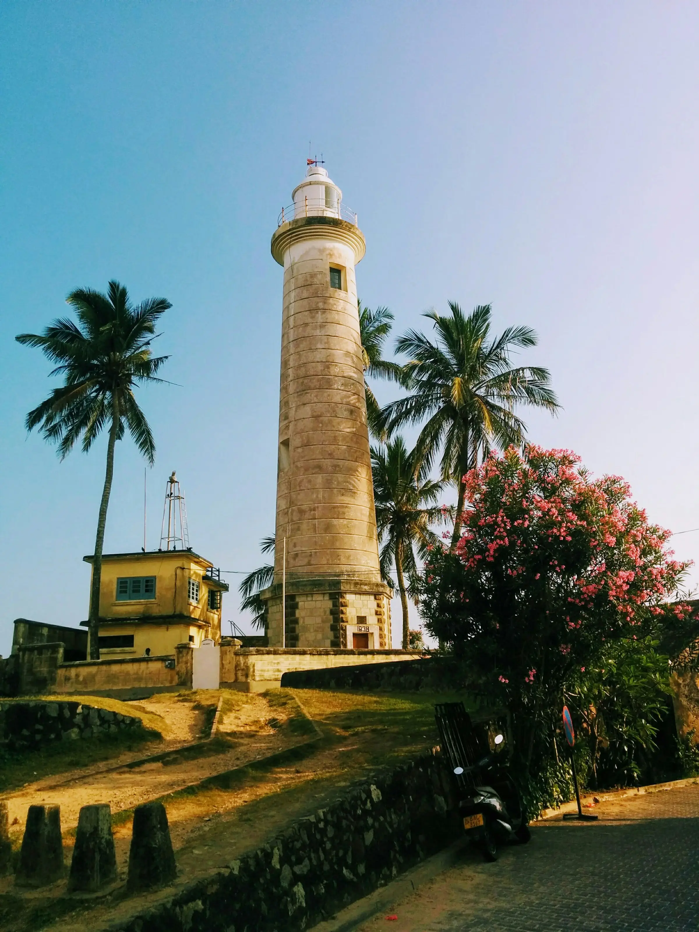 The white Galle Fort lighthouse standing above the ramparts among palm trees