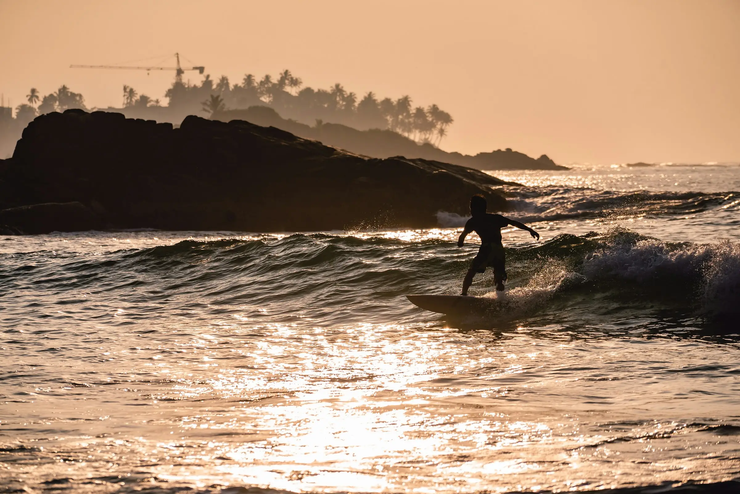 A surfer silhouetted against the sea at sunset